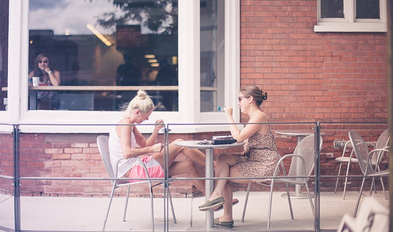 women talking outside at table